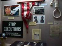 Photograph of the Capital Punishment Exhibit showing a noose, a partial American flag, and several anti-execution news articles.